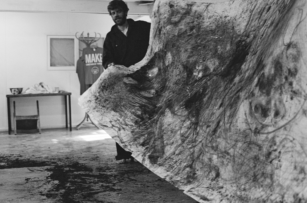 Residuals #2: Artist John holds one end of the completed drawing as it is taken out of the studio into the court yard outside the Shippon Artists Studios, Dartington Estate, Devon, England. Photo: Andrew Wood